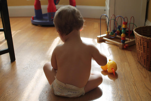Baby sitzt im Kinderzimmer und spielt mit seinen Spielsachen